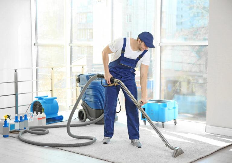 a professional cleaner wearing uniform vacuum cleaning a carpet.