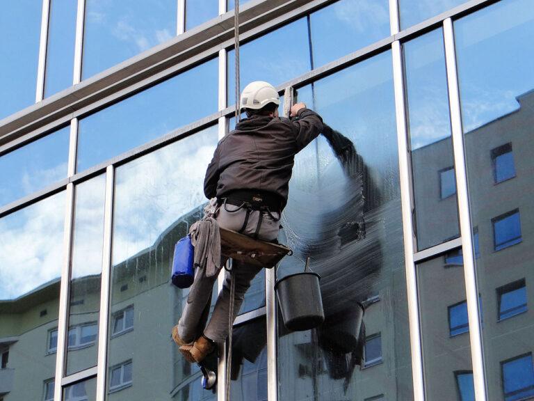 a man hanging outside a building a cleaning windows